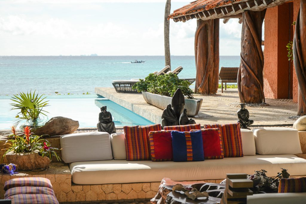 Sala hundida bajo la palapa con cojines artesanales, abierta a la alberca y al mar en Casa Corazón