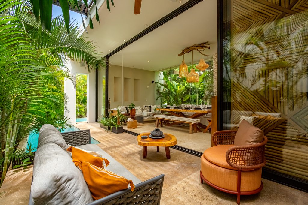 Sala de estar abierta al jardín con sillones y vegetación tropical en Casa de las Estrellas