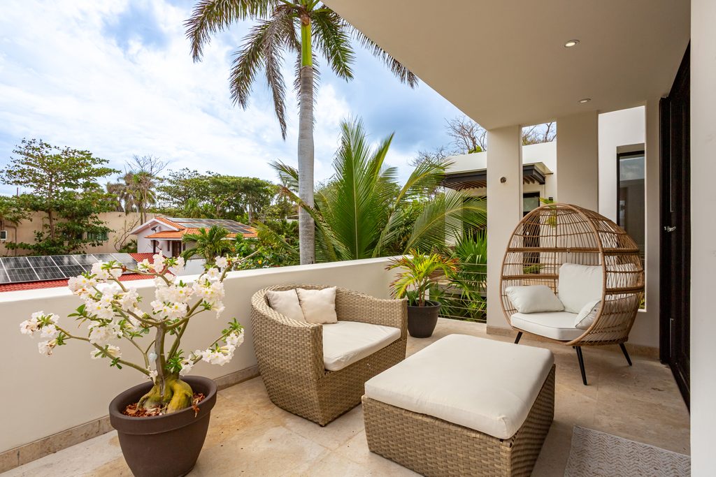 Terraza con sillones de mimbre y columpio colgante entre palmeras en Casa de las Estrellas